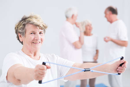 Active elderly woman exercising and smiling at the gym