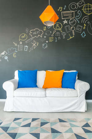 White couch with small colourful blue and yellow pillowsの写真素材