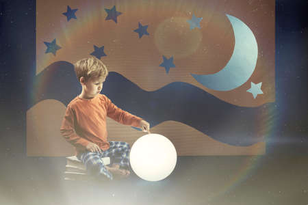 Little boys sitting on a books and pointing at the moonの写真素材