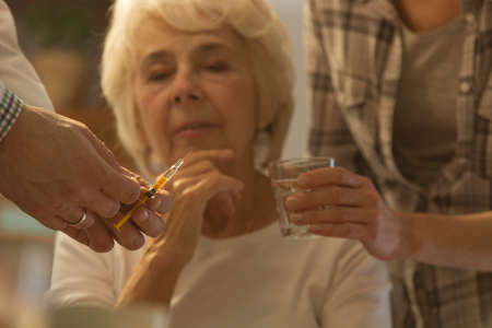 Doctor preparing the injection for his sick older patientの写真素材