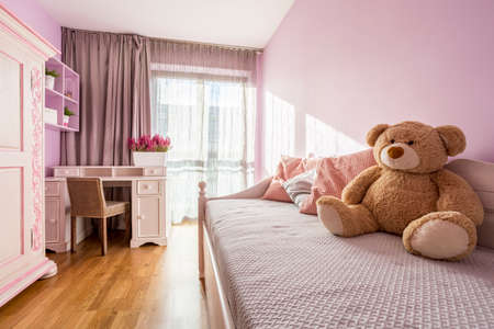 Teenage girl's pink bedroom with big teddy bear on a bedの写真素材
