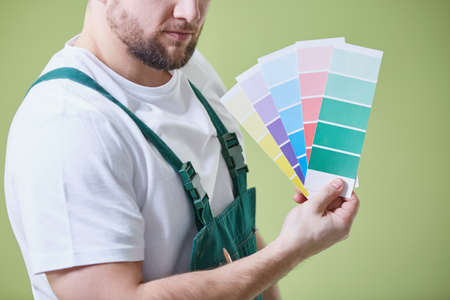 Young painter in uniform holding color palette of paintsの写真素材