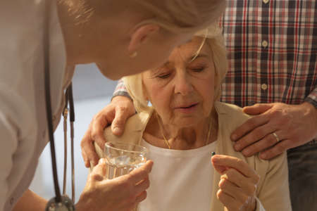 Elderly sick woman taking a medicine from the doctorの写真素材