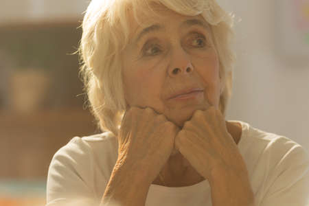 Close-up of pretty worried senior woman sitting alone