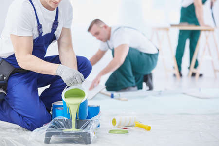 Professional interior construction worker pouring green color to paintの写真素材