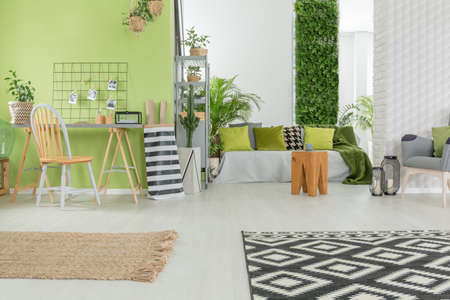 Bright apartment in green and white with desk and sofaの写真素材