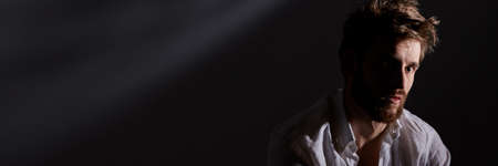 Lonely young man with mental disorder sitting in the darknessの写真素材