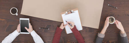 Businesspeople with tablet, clipboard and coffee in the officeの写真素材