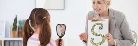 Little girl with mirror learning to pronounce the letters