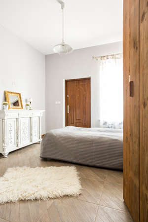 Comfy stylish bedroom with a large bed, a window and a small rugの写真素材