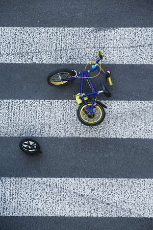 Small kid's bike lying on the road's zebra crossing after the car accidentの写真素材