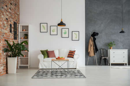 Grey and white loft interior with couch, dresser and chairの写真素材