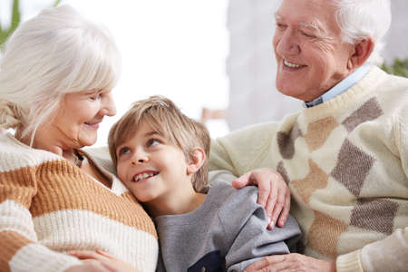 Family hug between happy grandparents and their smiling grandson