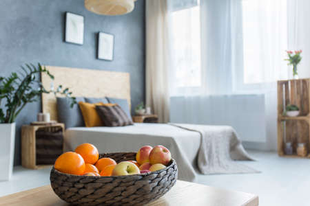 Modern bedroom with double bed and decorative fruit basketの写真素材