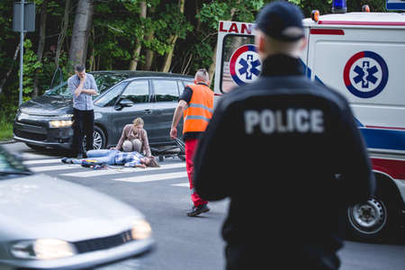 Car crash witness helping an unconscious victim with paramedic on his wayのeditorial素材