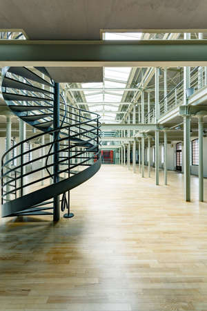 Industrial building interior with round staircase and wood floor