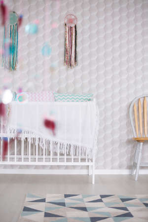 Crib against white wall in cozy modern nurseryの写真素材