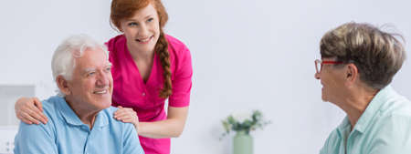 Young and beautiful nurse with plat taking care of elderlyの写真素材