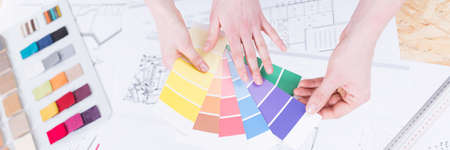 Hands choosing paint color samples for renovation