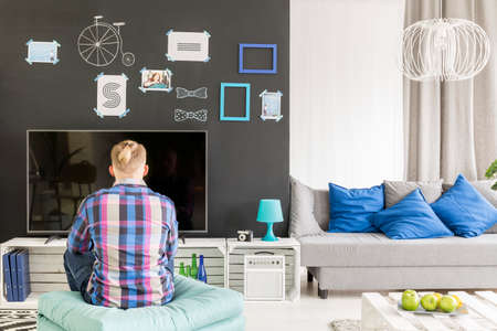 Young blond student sitting in front of plasma tvの写真素材