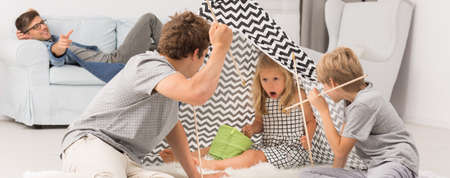 Teenage boy playing with younger siblings in tipi tentの写真素材