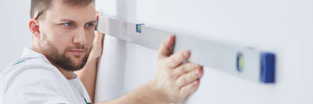 Builder checking wall with professional level, panorama