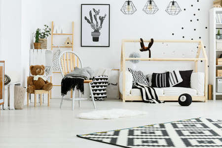 Baby room with wooden house bed, lamps, chair and rugの写真素材