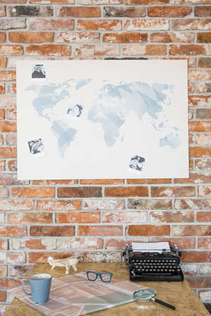 Desk with typewriter and map of the world against brick wallの写真素材