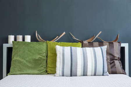 King-size bed with colorful pillows against black wallの写真素材