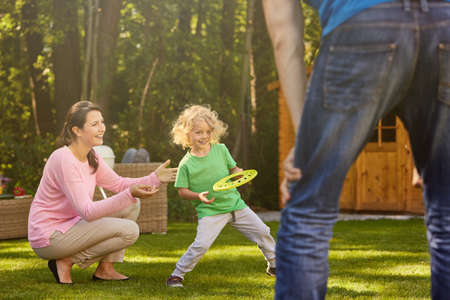Small boy playing with parents in gardenの写真素材