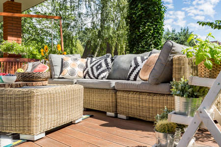 Modern garden patio with comfortable rattan sofa and small tableの写真素材