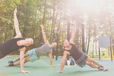 Three handsome friends exercising together in parkの写真素材