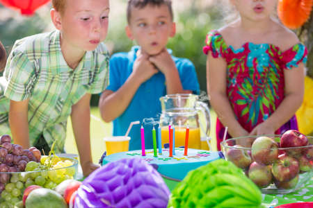 Small boy blowing up colorful candles on birthday cakeの写真素材