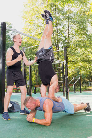 Men exercising together outdoors, doing plank and headstand