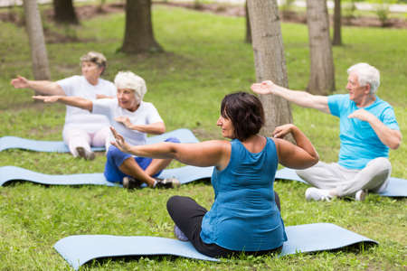 Shot of a group of elderly people exercising in a park with their trainer
