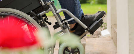 Man on a wheelchair trying to overcome the stairs barrier in the park