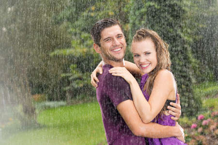 Happy man and woman standing in the summer rain