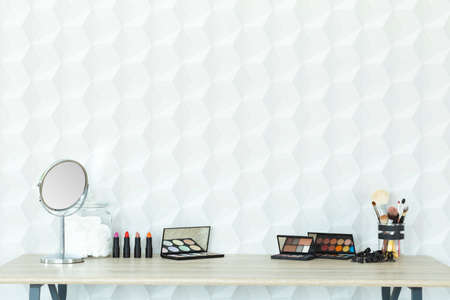 Makeup accessories on a wooden desk in modern room with copy space wallの写真素材