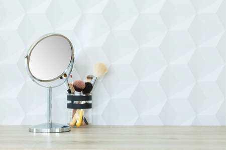Small mirror and makeup brushes on wooden deskの写真素材