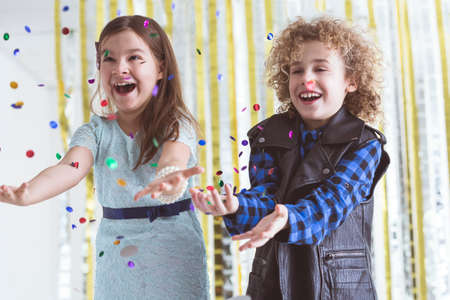Little couple during party throwing confetti