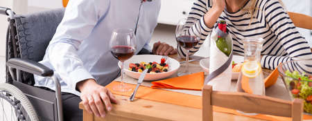 Shot of a man using a wheelchair having a romantic dinner with his wifeの写真素材