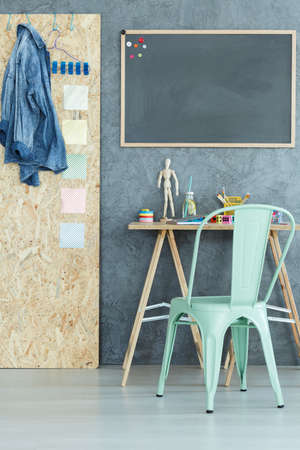 Modern room with grey wall, blackboard, desk and chairの写真素材