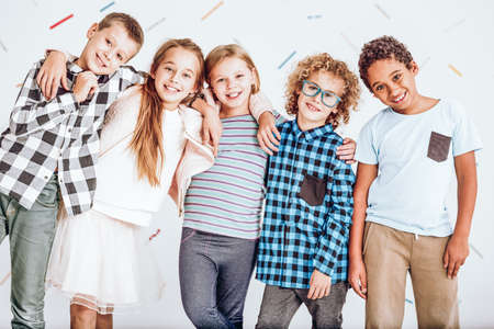 Group of smiling kids standing in a row and embracing each otherの写真素材