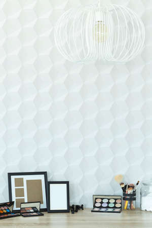 Desk with frames and cosmetics against stylish white copy space wallの写真素材