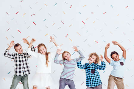 Group of kids standing with their hands up and having funの写真素材