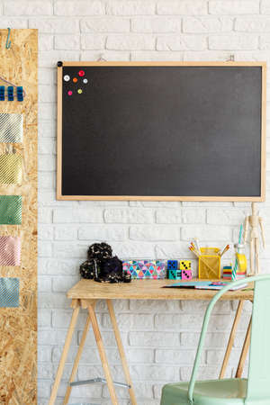 Modern room with blackboard on a brick wall and desk with accessoriesの写真素材