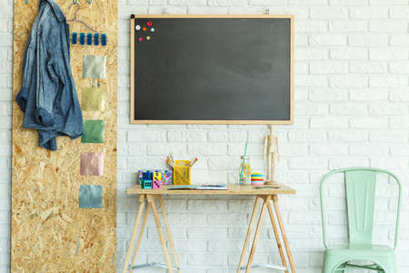 Desk, blackboard with magnets, chair and osb board in modern roomの写真素材