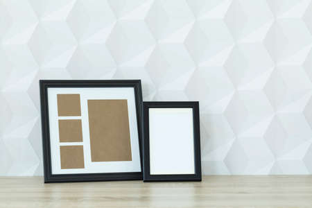 Two mockup frames on wooden desk against white wallの写真素材