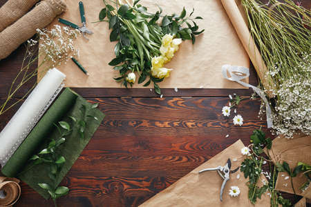 Wooden table in flower shop with roses and diy accessoriesの写真素材