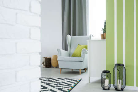 Cozy flat with armchair, white dresser and green wallの写真素材